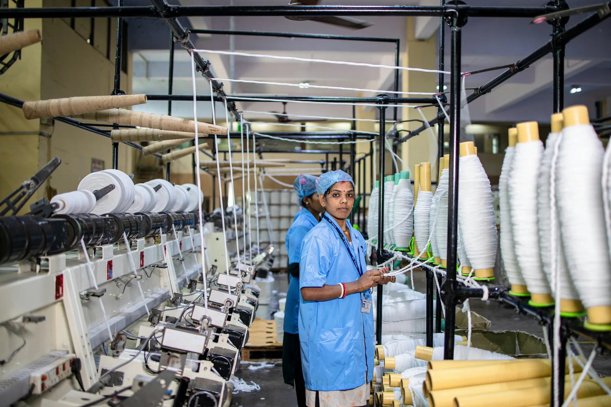 Operaria controlando hilos en una planta textil